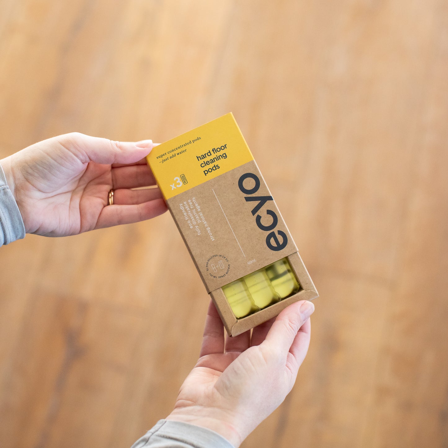 woman holding a 3 refill pack of eco-friendly and organic floor cleaner pods from ecyo