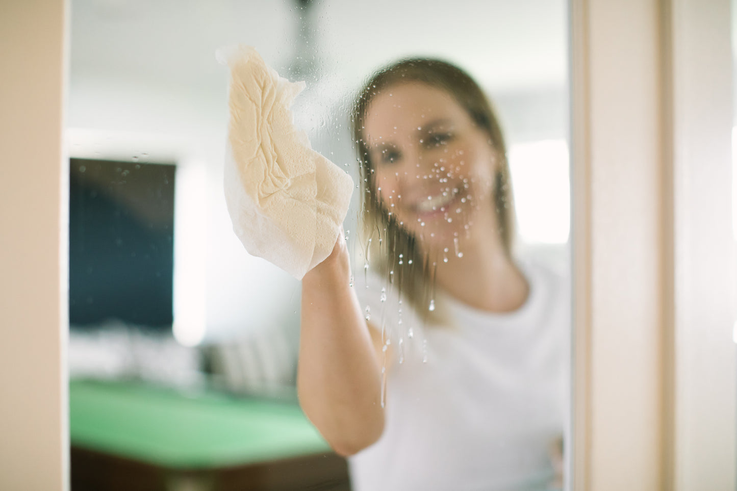 view of eco window cleaning spray on a mirror with woman blurred out in background